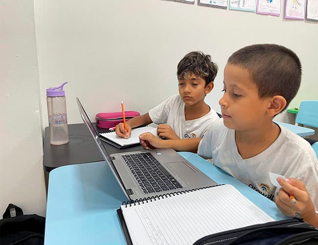Dois alunos pesquisando juntos no notebook
