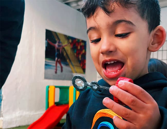 Criança da educação infantil brincando com bolhas de sabão
