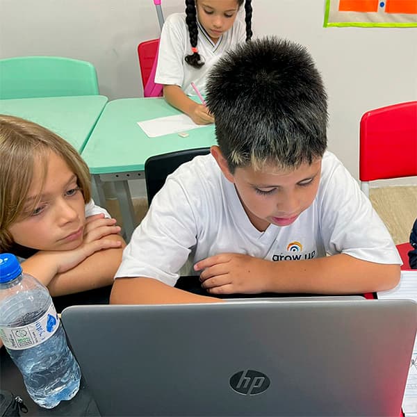 Aluno do fundamental I pesquisando no notebook enquanto a colega acompanha ao lado