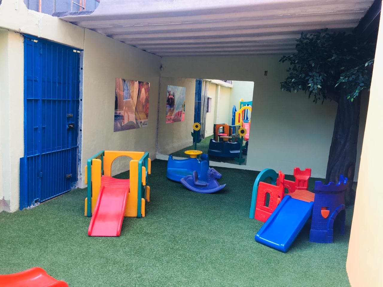 Playground coberto da Grow Up School com grama sintética, escorregadores e brinquedos de plástico