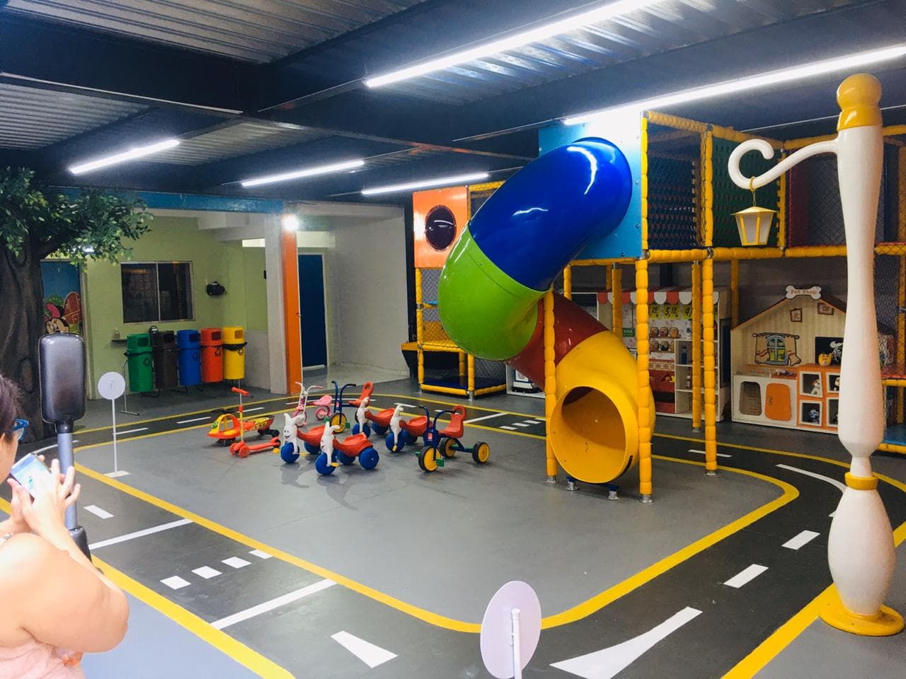 Espaço interno de psicomotricidade da Grow Up School com circuito de trânsito, triciclos e escorregador tubular
