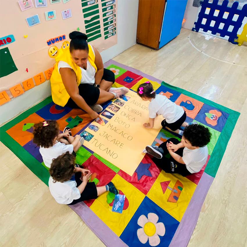 Educadora em roda de leitura com as crianças sobre o tapete