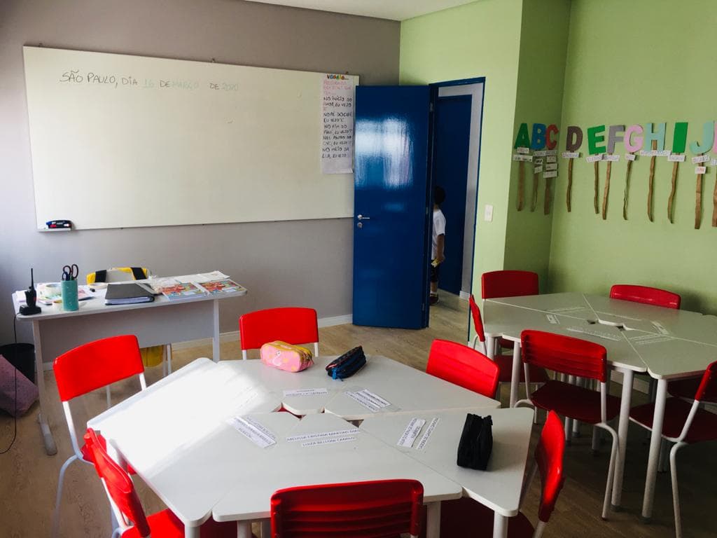 Sala de aula da Grow Up School com lousa branca, cadeiras vermelhas e alfabeto na parede