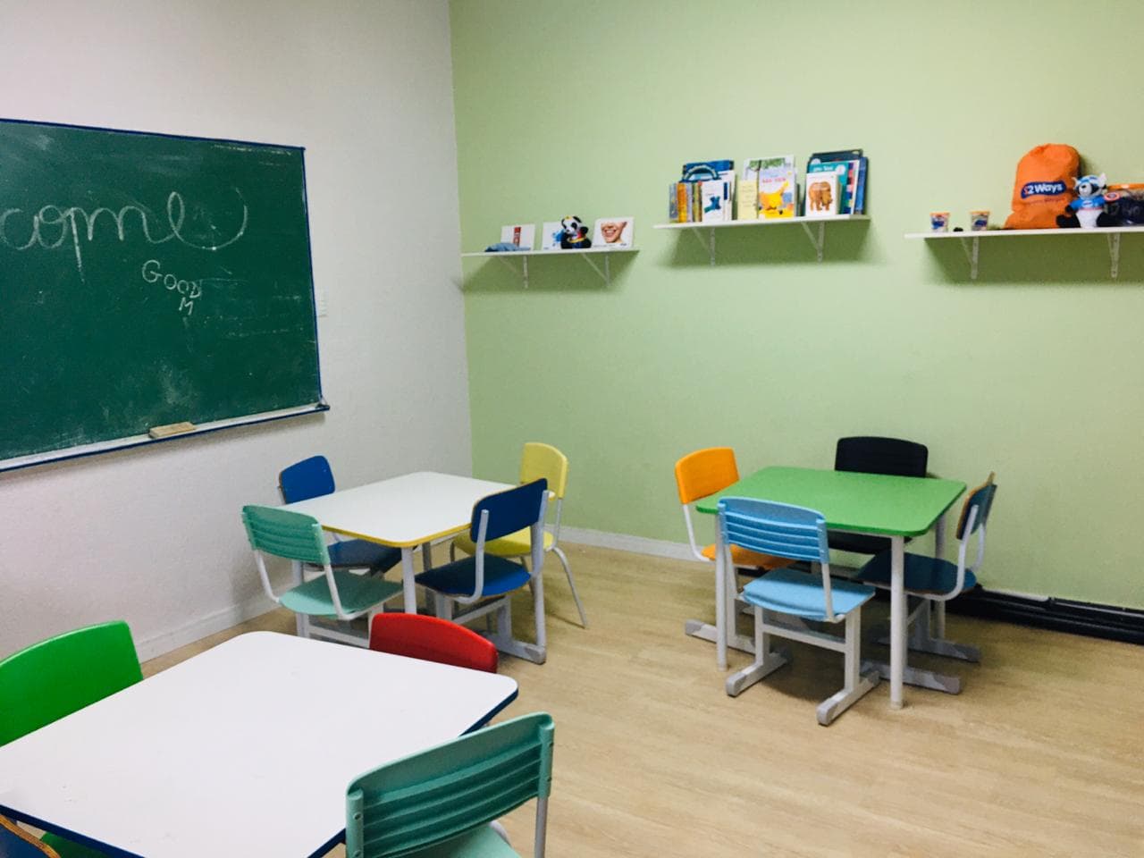 Sala da educação infantil da Grow Up School com lousa verde, mesinhas coloridas e prateleiras de livros
